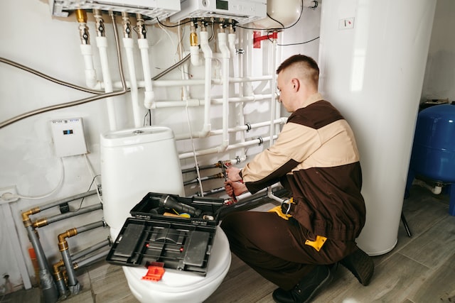 a plumber repairs a pipe in the toilet