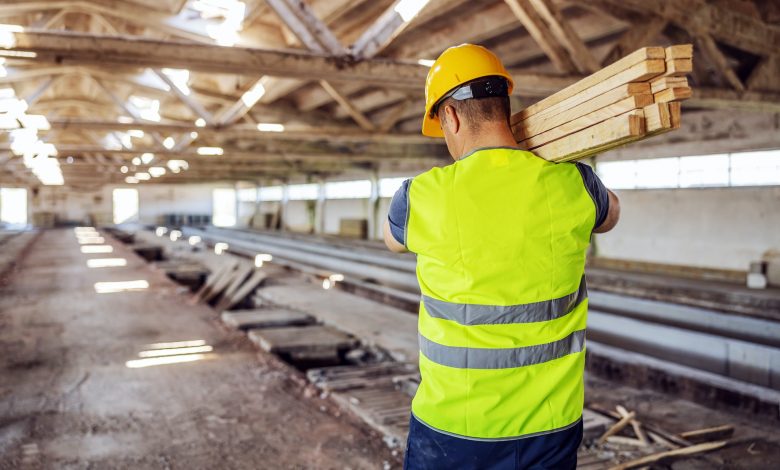 Rear view of hardworking construction worker holding joists