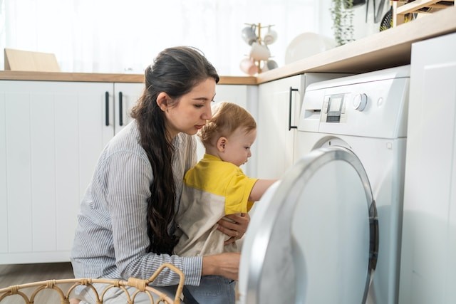 young mom doing housework with baby boy toddler in kitchen