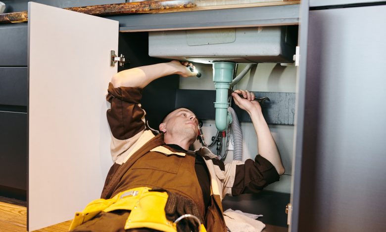 plumber fixing new pipe under sink with wrench