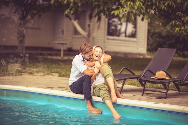 Happy smiling couple sitting by the pool