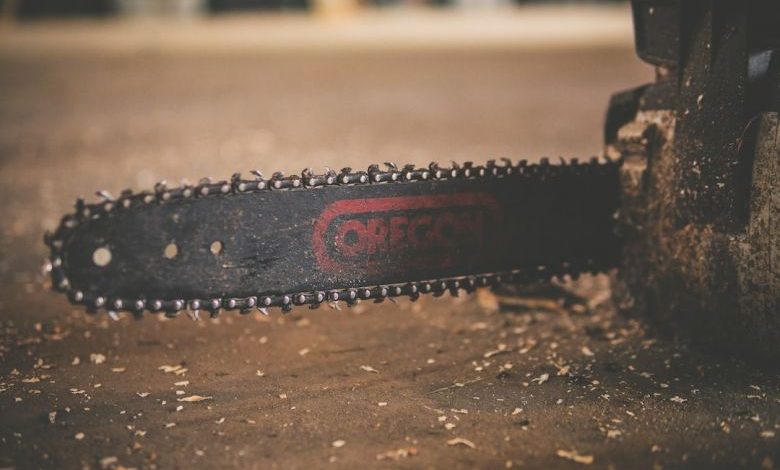 Chainsaw - black and red Oregon chainsaw on brown wood plank