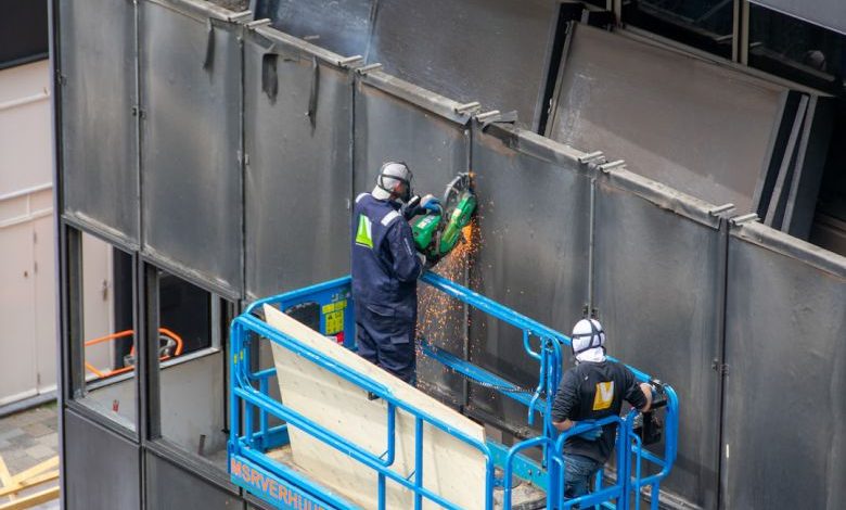 Demolition Tools - a couple of men standing on top of a metal structure