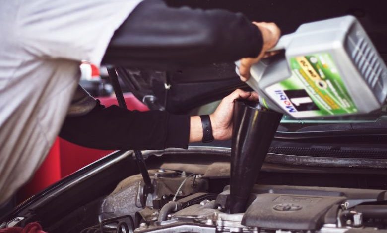 Car Maintenance Tools - man refilling motor oil on car engine bay