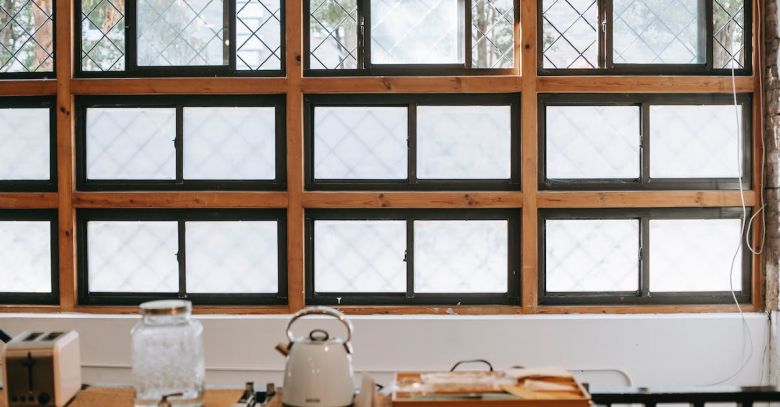 Kitchen Storage Space - Kitchen interior with fenced window near table with electric appliances and bottle of water with tap in house