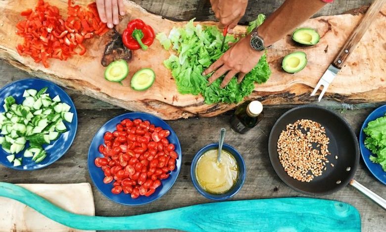 Outdoor Kitchen - person slicing green vegetable in front of round ceramic plates with assorted sliced vegetables during daytime