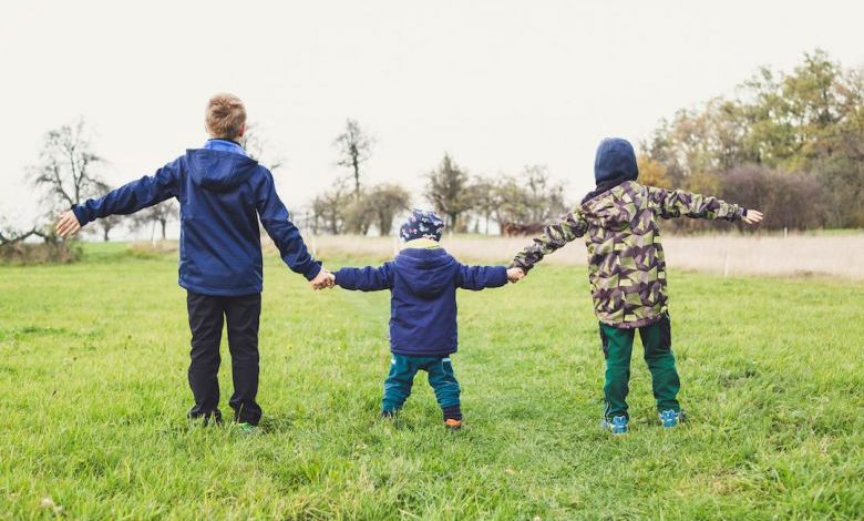 Children Play Area - three children holding hands standing on grasses