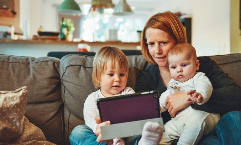 Child-safe Home - two babies and woman sitting on sofa while holding baby and watching on tablet