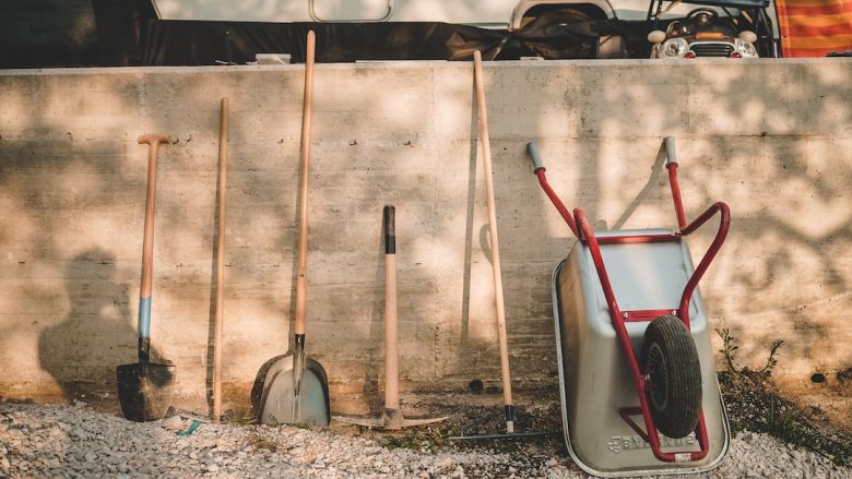 Gardening Tools - red and black shovel beside brown wooden stick