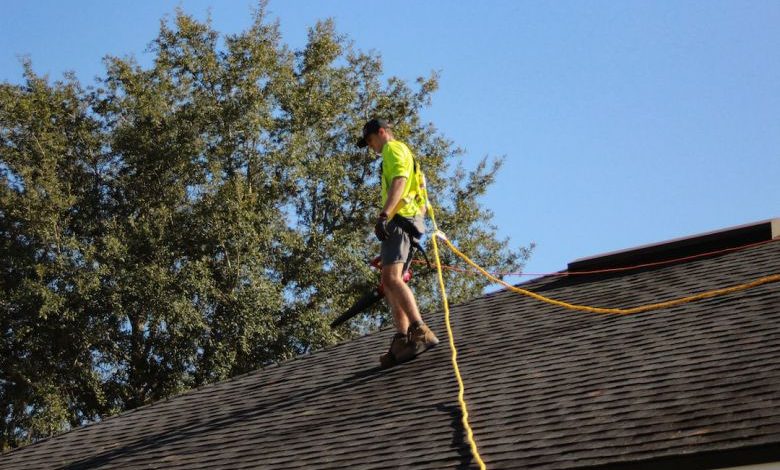 Roofing - a man on a roof working with a rope