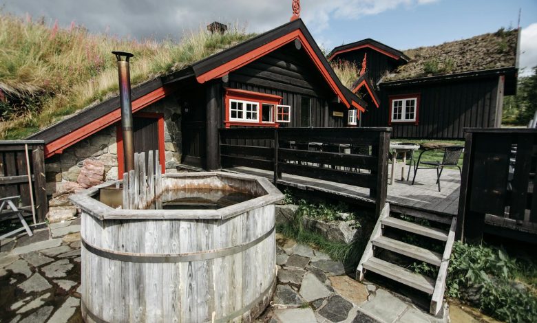 Charming rustic cabin exterior with a vintage wooden hot tub in a lush outdoor setting.