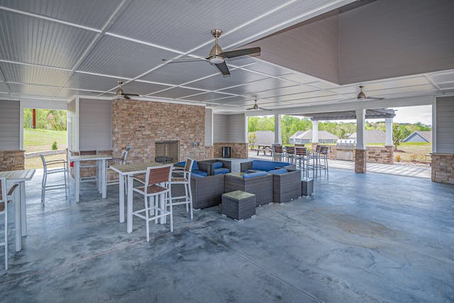wooden-tables-and-chairs-beside-black-sofa-in-the-patio