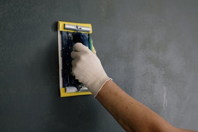 crop-man-scarpering-gray-wall-in-flat